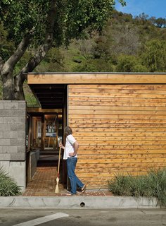 Compound Addition - Photo 7 of 12 - Flanking the concrete wall is a carport and an entrance leading past a small, cedar-clad ancillary building for art projects and laundry.
