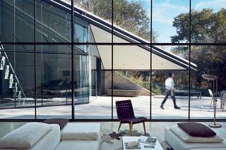 10 Modern Glass Homes - Photo 9 of 10 - Edgeland House, built on a cliff-top lot in Austin by architect Thomas Bercy for lawyer and writer Chris Brown, is topped by a living roof that helps it blend into the landscape. The concrete, steel, and glass house is divided into two distinct public and private halves.