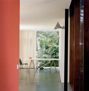 The Tree of Ghent - Photo 3 of 11 - Van Everbroeck’s home office occupies the end of one arm of the building. An industrial outdoor light fixture is mounted on a black-painted steel post. The orange of the back wall was chosen to work with the glowing rays of the sunset and the silhouetted, dancing shadows of leaves.