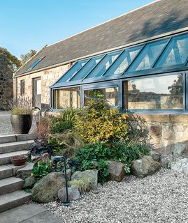 The glass balustrade and floor were sourced in Germany and installed by James Aiken. Angelique, the founder of Papillon Designs and Landscaping, clustered plantings around the exterior glass addition.