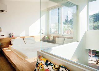 Odd Angles Don't Stop This Apartment's Transformation - Photo 6 of 8 - Ritenour carved a window into an L-shaped wall to open the cramped master bedroom to a small, light-filled atrium (below). An unsightly structural beam was covered with wood to create a distinctive sunken bed.