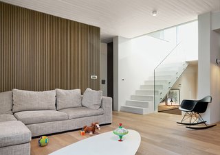 Odd Angles Don't Stop This Apartment's Transformation - Photo 7 of 8 - Angeliki’s toys share space in the living room with an ETR coffee table and Molded Plastic Rocker chair, both by Charles and Ray Eames and purchased from Vitra. Behind the couch, 300 vertical oak strips add a decorative element.