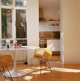 The kitchen spills out into the living room, where the focus is on a Saarinen Tulip table, Eames fiberglass shell chairs, and lamps by Achille Castiglioni.