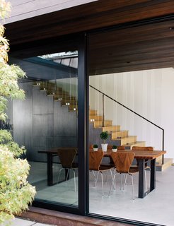 Modern Home Designed for Live Music in Beverly Hills - Photo 4 of 10 - The new volume houses the dining area, which includes stairs to the bedrooms. The table is from Blake Avenue and the walnut chairs are from Room & Board. "You don’t want bright colors to take away from that relationship between the interior and the exterior," Walker says.