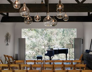 Modern Home Designed for Live Music in Beverly Hills - Photo 8 of 10 - Located in the renovated barn, the living room can be transformed into a performance space that seats 80. The art piece is from South Africa. Accompanying the Steinway piano is a sideboard from Restoration Hardware; the pendants are from Cisco Home.