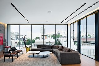 The living room features stunning views of the city, a Bend sofa and Phoenix coffee tables, both by Patricia Urquiola for B&B Italia and Moroso, respectively, and two Gray armchairs by Piero Lissoni for Living Divani.