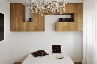 Designed by architect Lidija Dragisic, this home in Slovenia is filled with unusual shelving—and the master bedroom proved to be no different. A maze-like set of cabinets and shelves rests above the head of the bed, providing closed and open shelving. Set against the white walls and curtains, the wood provides a contrast while the shape of the shelves is almost sculptural.