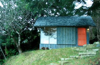 A recycled barndoor track and wheels affords privacy behind a siding covered panel.