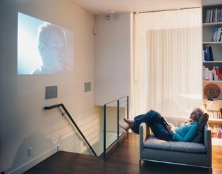 Wireless wonderland: One way to reduce clutter is by stashing most of the media hardware downstairs and jettisoning the television. When it’s time to show a DVD, the wall does double duty as a movie screen.