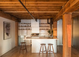 This Cozy Home Totally Changes How We Think of Tribeca Lofts - Photo 1 of 9 - The custom zinc cabinets and quartzite countertops of Mark Berryman’s Tribeca apartment reflect the sun as it sets over Manhattan. Workstead designer Robert Highsmith kept the apartment’s original fir beams and painted its existing pipes Onyx by Benjamin Moore. The counter stools are by Sawkille, and the floors are white oak from LV Wood. The range is by Viking.