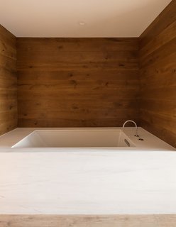 This Cozy Home Totally Changes How We Think of Tribeca Lofts - Photo 3 of 9 - Replacing the dated bathrooms was a priority of the renovation. Highsmith embraced the tight quarters, cladding the walls in horizontal oak boards. The custom tub surround in the master bath is Calacatta marble from ABC Worldwide Stone. The fixtures are by Zucchetti.