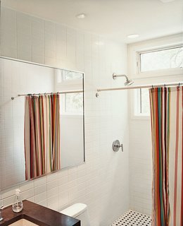 Take Me Home - Photo 6 of 7 - A brightly striped shower curtain lends bright punctuation to an otherwise austere bathroom.