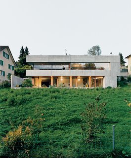 25 Modern Homes That Kill it With Concrete - Photo 1 of 25 - The rear of the house looks onto a lush backyard. The rough, industrial prefabricated concrete panels by the German manufacturer Syspro are the building blocks of the home.