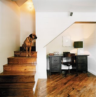 From the stairs West looks across the living room over the salvaged pine floors, which run throughout the house.