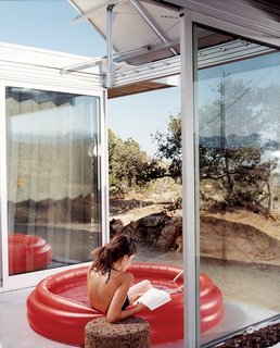 iT House, Joshua Tree - Photo 4 of 9 - The living space and bedrooms are separated by two small courtyards. Linda Taalman reclines in a small, inflatable wading pool in the home's "firecourt," facing south toward the desert.