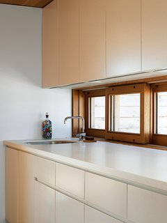 Upstairs in the Floating House, building codes didn't allow a full kitchen, but a galley kitchenette continues the compound's simple palette of white and Douglas fir. "I love how understated it is," says Worple.
