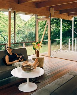 Lava Flow 4, The Big Island - Photo 2 of 9 - The living area, with its pair of sleeper sofas and Ikea coffee table, doubles as the guest bedroom when not being enjoyed by Kurokawa. It is framed by floor-to-ceiling screen walls. Details of the home's construction, such as the simple cuff that attaches post to beam, are purposefully left exposed.