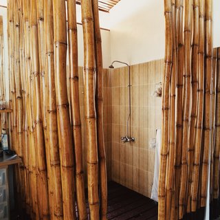 An Inno-native Approach - Photo 9 of 9 - The six-by-six-foot shower boasts a hardwood-slatted deck, which allows water to seep into a concrete pan that empties into the main drainage system. The cage of bamboo poles provides the requisite privacy to the bather.