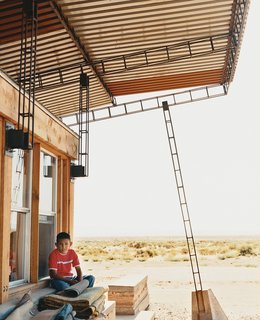 No Grid in Sight - Photo 3 of 8 - Nicholas sits in the shade of the roof; students cut and hand-welded thousands of reclaimed rebar pieces into a complex grid that would support four bi-level <br><br>corrugated-steel roof panels.