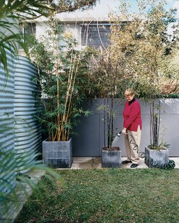 In the garden, Mary Henning gives her potted plants a much-needed drink of graywater diverted from the kitchen and bathrooms and filtered by a massive green wall.