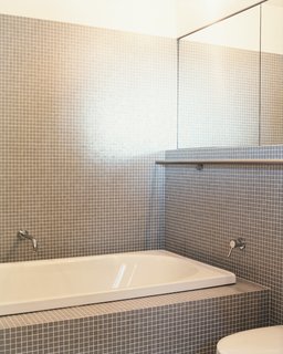 A stainless-steel towel bar runs the length of two walls in the master bathroom.