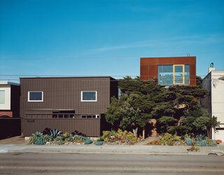 This Surfer's Beach House is More Than It Seems - Photo 1 of 13 - The original house (left) only gave two glimpses of the vast Pacific Ocean out of the west-facing windows—an unusual choice given the epic sweep and clear cachet of an uninterrupted ocean view. Aidlin Darling Design took a different tack with the new addition (right), using the cypress trees as a natural screen to shield the lower levels while opening the third floor to stunning views. The Cor-Ten steel cladding on the new house is designed to further redden and rust with the help of the obliging sea air.