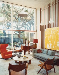 This Surfer's Beach House is More Than It Seems - Photo 11 of 13 - Born outfitted the living room of the original house with vertical slats on which to mount any manner of visual material. Artwork becomes easy to move around, but Lloyd-Butler likes the placement of a painting by Wayne Gonzales depicting Lee Harvey Oswald.