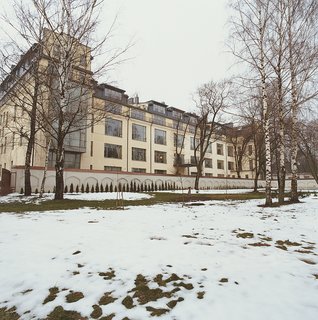 The renovated façade of Mikulionis’s flat, seen beyond thin snow and bare trees from the grounds of the monastery.
