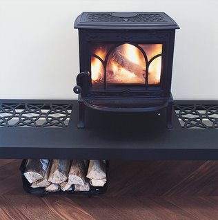 The wood stove roars atop a table designed by the architect.