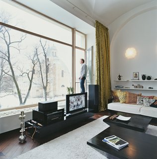 The architect looks toward the grounds of an 18th-century monastery, which accompanies the domed church. The large hi-fi system with Infinity acoustics is three centuries newer than the building behind it. The wall sconces are from Luzifer Lamps in Spain. Their pattern of triangular prisms is reminiscent of ceilings in the domes of the Alhambra, the ancient Moorish palace in Andalucia. The shelves are stocked with souvenirs from Mikulionis’s travels—throughout both Europe and former Soviet states like Uzbekistan and Ukraine.