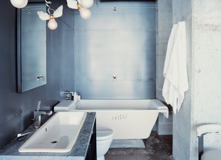 10 Ideas For the Minimalist Bathroom of Your Dreams - Photo 6 of 10 - Winged light bulbs, part of an Ingo Maurer fixture, bring levity to this bathroom. The space features a zinc wall by Houston metalworker George Sacaris, who also did the bathroom and kitchen cabinets.