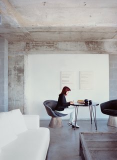 With bright red hair, Hill is a standout in a gray-glass 1960s building. Her coffee table is a French mail-sorting table with the legs cut down.