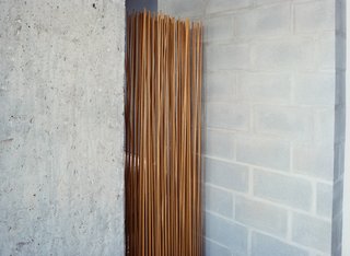 A room divider by Extremis, made of sticks protruding from a rubber base, shields the bathroom.