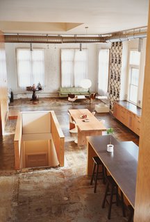 A Minneapolis Building That Has Lived Multiple Lives Is Revitalized by a Coffeehouse Owner - Photo 1 of 10 - A few carefully chosen furnishings punctuate the light-filled living area that sits adjacent to the kitchen, like Buttercup Chairs by Blu Dot, a lightbox and screen print by artist John Vogt, and a kelly green vintage couch.