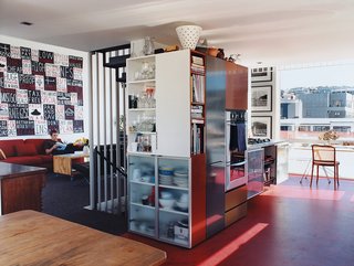 A densely packed built-in unit divides the kitchen area from the living room, and provides streamlined storage for appliances and kitchenware. The Bieringas are avid collectors of New Zealand art; the painting to the left is by Peter Robinson, and the many photographs peppering the apartment are by important Kiwi artists Luit has championed over the years.
