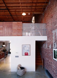By leaving the exterior walls of the neighboring structures exposed on their interior, Miro and Weiss guaranteed that the neighborhood’s history would be a part of their new home. Raw plywood and industrial-strength steel railings are balanced with custom finishes and signs of domesticity.