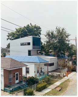Bild Design introduced the new structure seamlessly with the help of builders A.J. Christiana Construction. Ms. Doris, whose tarp-clad house to the left lost much of its roof when Hurricane Katrina struck, checks out her new neighbor.