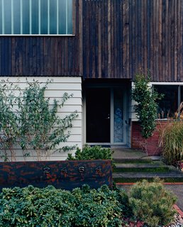 The home’s entry as it is today is a planar collage of right angles and various materials. White reused as much of the original home as possible, such as the siding seen here, and added a second story.