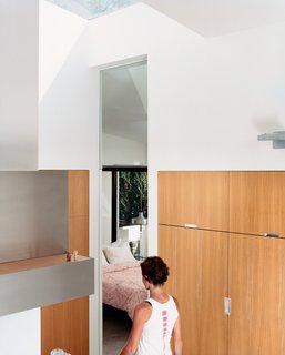 Venetian Vicissitude - Photo 1 of 9 - Dawn Farmer walks from the kitchen to a guest bedroom. The seven-foot-tall doorway lines up with the glass doors and cabinetry throughout the house—which is made of <br><br>13-layer multi-ply apple core with rift-oak veneer.
