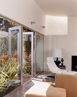 Venetian Vicissitude - Photo 2 of 9 - Seven-foot-high glass doors bring the garden, landscaped by Jay Griffith, into the living room. A skylight brings even more light into the white-walled room with polished-concrete floors. There is a splash of color in a custom rug designed by Dawn Farmer and made by Della Robbia, which also made the sofas.