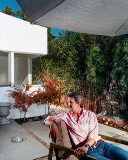 Venetian Vicissitude - Photo 8 of 9 - The front, middle, and rear yards are conceived as outdoor rooms. Pierre Kozely relaxes <br><br>in the middle yard in a prototype of an outdoor furniture line by Pietrarte. A bronze Ganesh is on a raised pedestal in the middle of a small water feature.