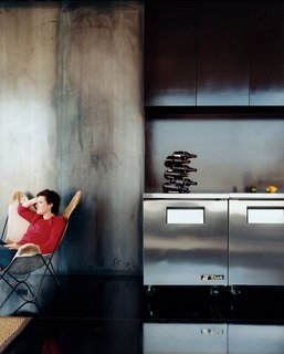 Cold-rolled steel walls lend a bluish tint to the kitchen, which features cabinetry made of NAP, or North American plywood, which is a very dense plywood with a natural chocolate-colored finish.
