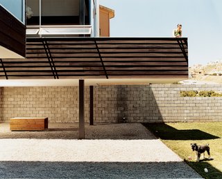 Paola Gracia keeps an eye on Kata, one of the couple’s schnauzers, from the second- story balcony. In the shade below the balcony is the dogs’ house, meant to mimic the Gracias’, that architect Jorge Gracia built from leftover building materials.