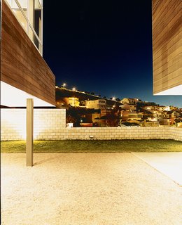The two structures that comprise the house frame views of the ever expanding city. The backyard is perfect for frolicking dogs and children, with concrete block walls just high enough to keep them in but low enough to not keep the city out.