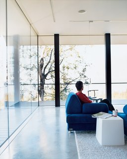 50 Modern Homes With Floor-to-Ceiling Windows - Photo 11 of 50 - The floor-to-ceiling windows in the living room give the impression of being outside even while cozily enjoying a cup of tea inside. All the windows in the house are double-paned and filled with argon gas. Petra Sattler-Smith says that "even when it’s 10 below, you can put your hand on them and they are still warm." Hydronic radiant heating embedded within the concrete floors not only enables barefoot walking during the coldest months, but also warms the furniture and everything else in the room.