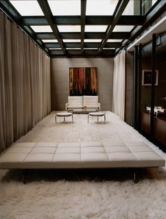 The industrial aesthetic of the Segals’ lounge area is softened by a white shag rug and the generous sunlight that streams through its ceiling of thick glass. The seating is by Paul Kjaerholm.
