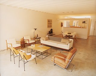 Bringing Families Back to Downtown Dallas - Photo 2 of 9 - The living room of Baum’s 1650-square-foot home features a poured-concrete floor as well as many vintage finds and artifacts from his travels. The sidechairs in the foreground are by Ib Kofod-Larsen and the leather chair is by Gilbert Rohde.