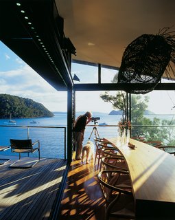 Three Glass-and-Copper Pavilions Conquer the Cliffs - Photo 6 of 10 - Dougal James-Robertson studies the expansive views that extend all the way to the Barrenjoey headland many miles away with the use of a handy telescope. The sliding glass wall makes the kitchen feel like an outdoor room.
