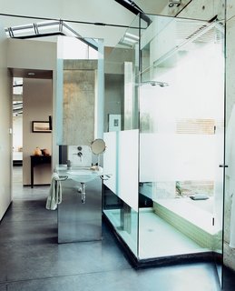 The dramatic bathroom features a glass sink designed and cast by Mies Grybaitis of OIA. The etched glass shower is accented by green glass tile.