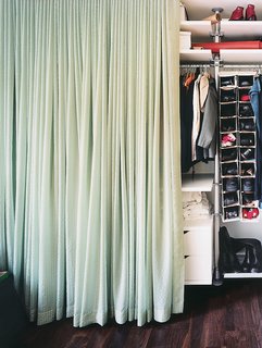 The contents of the 15-foot-long closet, concealed by a long swath of calming blue-green fabric, glows like a light box when illuminated from within.